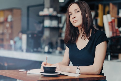 SEO Optimized Article Writing Services attractive girl sitting at desk with pen and coffee thinking