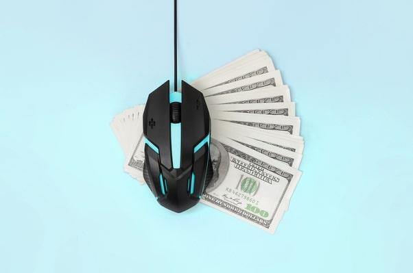 Black PC Mouse on top of dollar bills with light blue background indicating PPC (Pay-Per-Click) Advertising